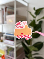 Le sticker « et c'est okay » photographié, prêt à coller