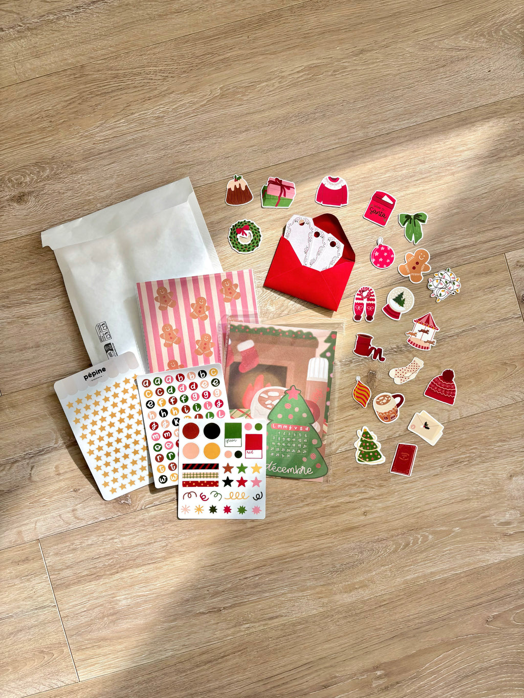 Contenu de la Box de Noël photographié sur un parquet : stickers, planches et pochette
