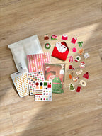 Contenu de la Box de Noël photographié sur un parquet : stickers, planches et pochette